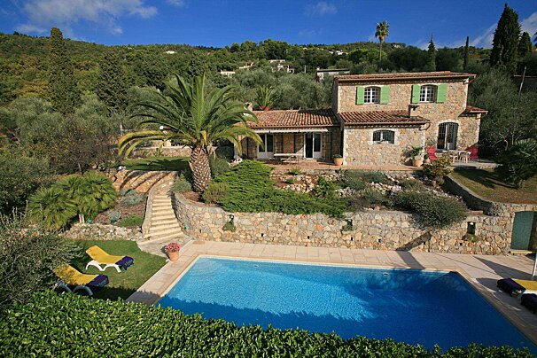 A large stone house with a swimming pool in front of it